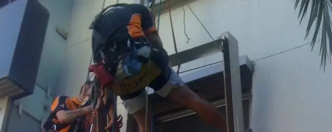 Working on ropes, Two rope access technicians working at a window frame on the side of a building.