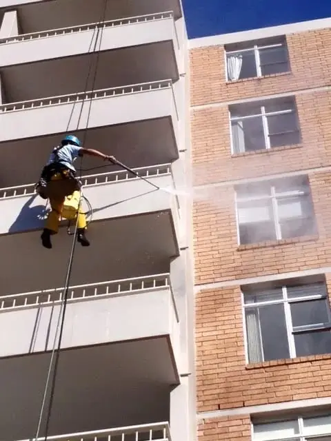 Abseiler pressure washing the brick facade, 3–7 Bariston Ave, Cremorne