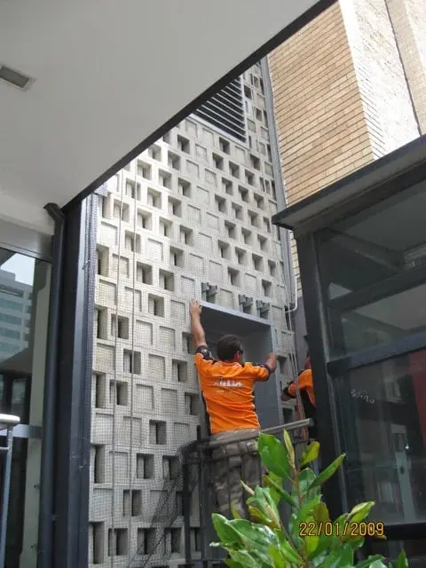 OneVision technician on a ladder installing bird control on a feature wall, Guide Dogs, Chatswood