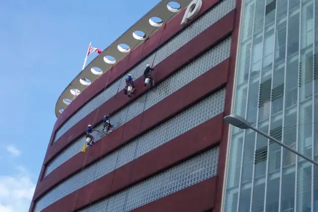 Abseilers cleaning windows on the red curved facade, Peejays, Sydney