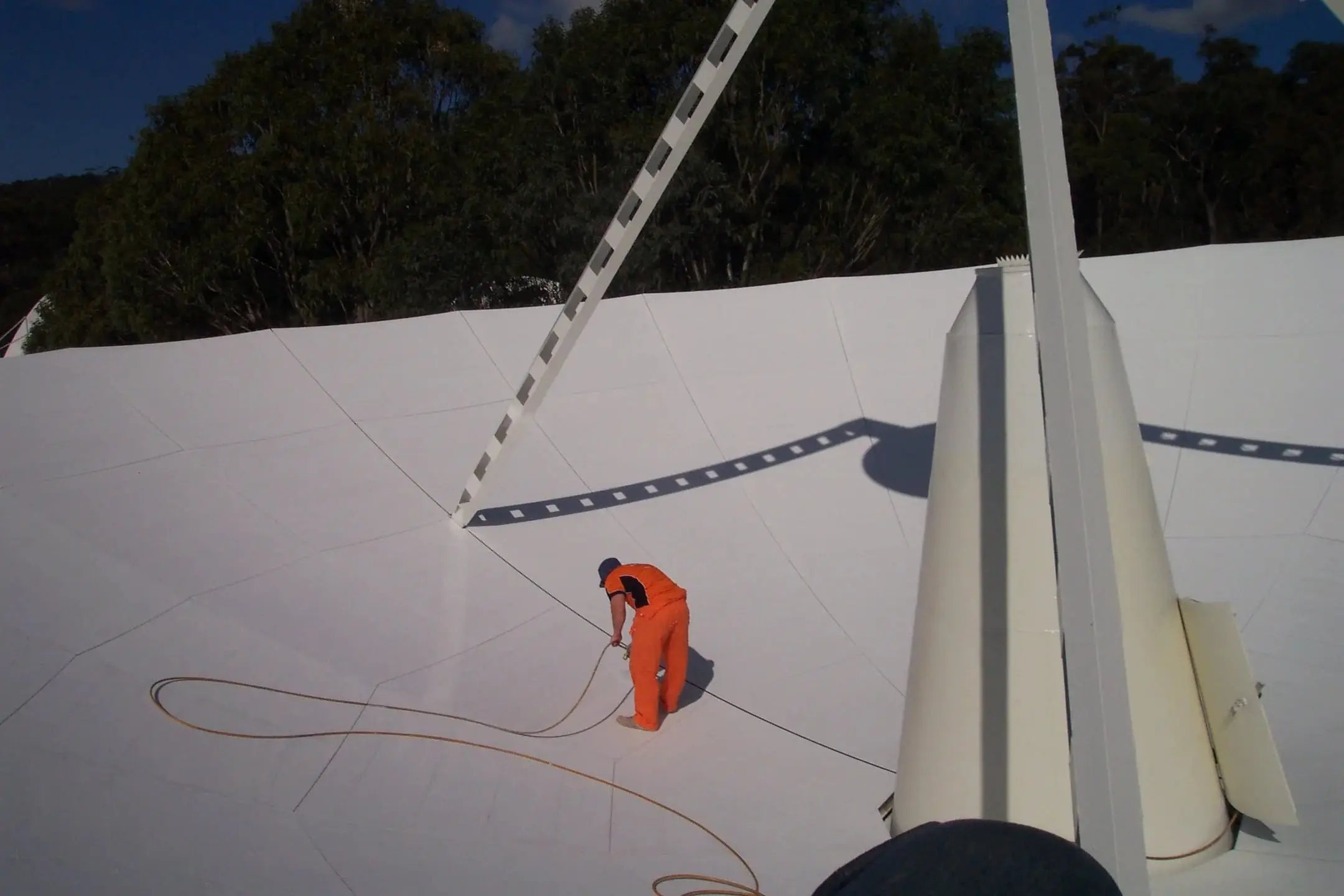 OneVision technician with a hose on the face of a large satellite dish