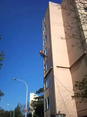 Facade inspection, A roped technician on a tall rendered facade.