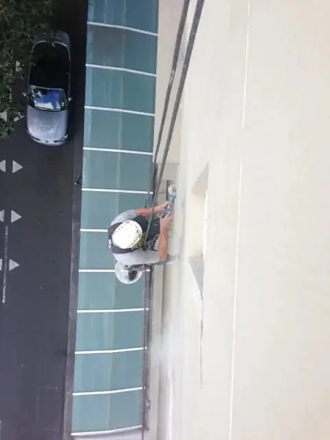 Working on ropes, Looking down on a rope access technician working on a painted wall above a glass canopy and the street.