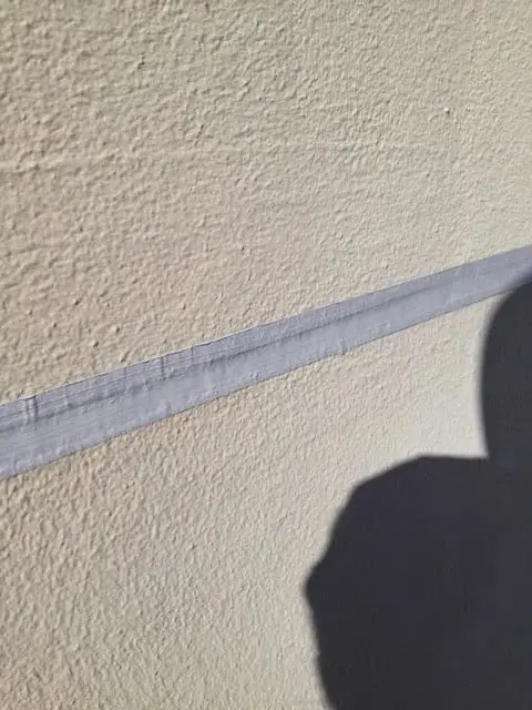 Sealed joint, A straight grey sealed joint across a textured painted wall.