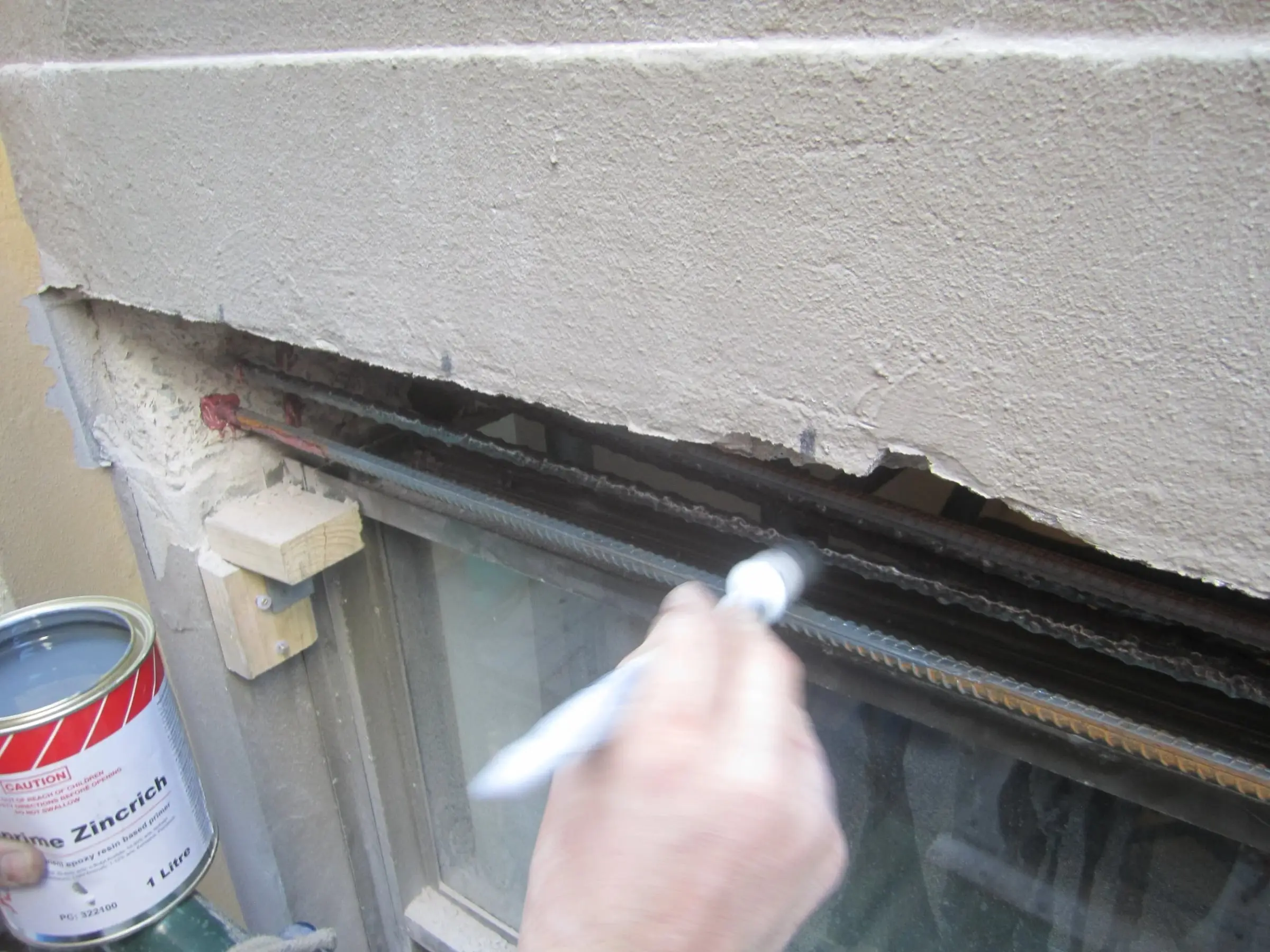 Treating the steel, Exposed reinforcing bars being brushed with a zinc-rich primer before the concrete is reinstated.