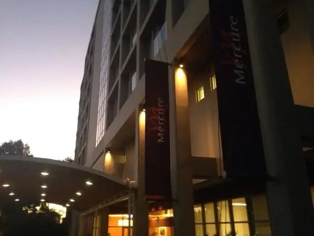 Hotel entrance lighting, A hotel entrance at dusk with Mercure banners, lit uplights on the facade and downlights under the entry canopy.