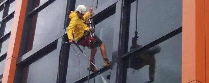 Washing the glass, A technician in a raincoat washing a glass facade.