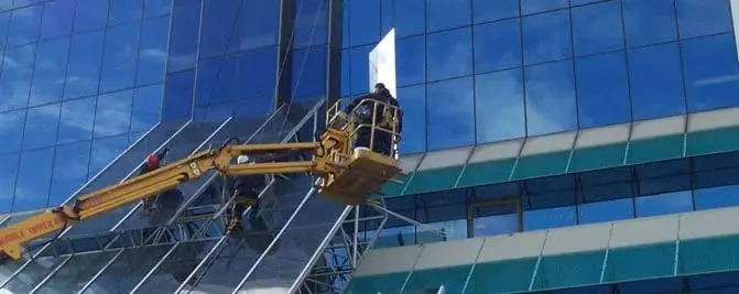 Glass from an elevated work platform, Workers in an elevated work platform basket at a sloping glass curtain wall on a high-rise.