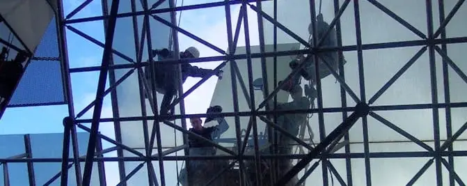 Glazing a space frame, Technicians on ropes inside a steel space frame, working on a large glass panel.