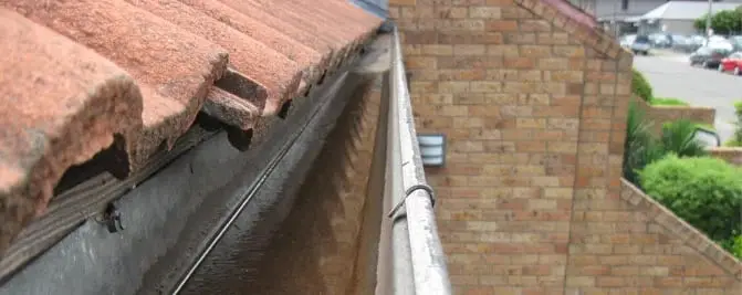Clean gutter, A cleared gutter below a terracotta tiled roof.