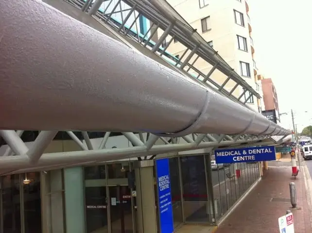 Street awning gutter, A long round gutter running the length of a glass street awning over a row of shopfronts.