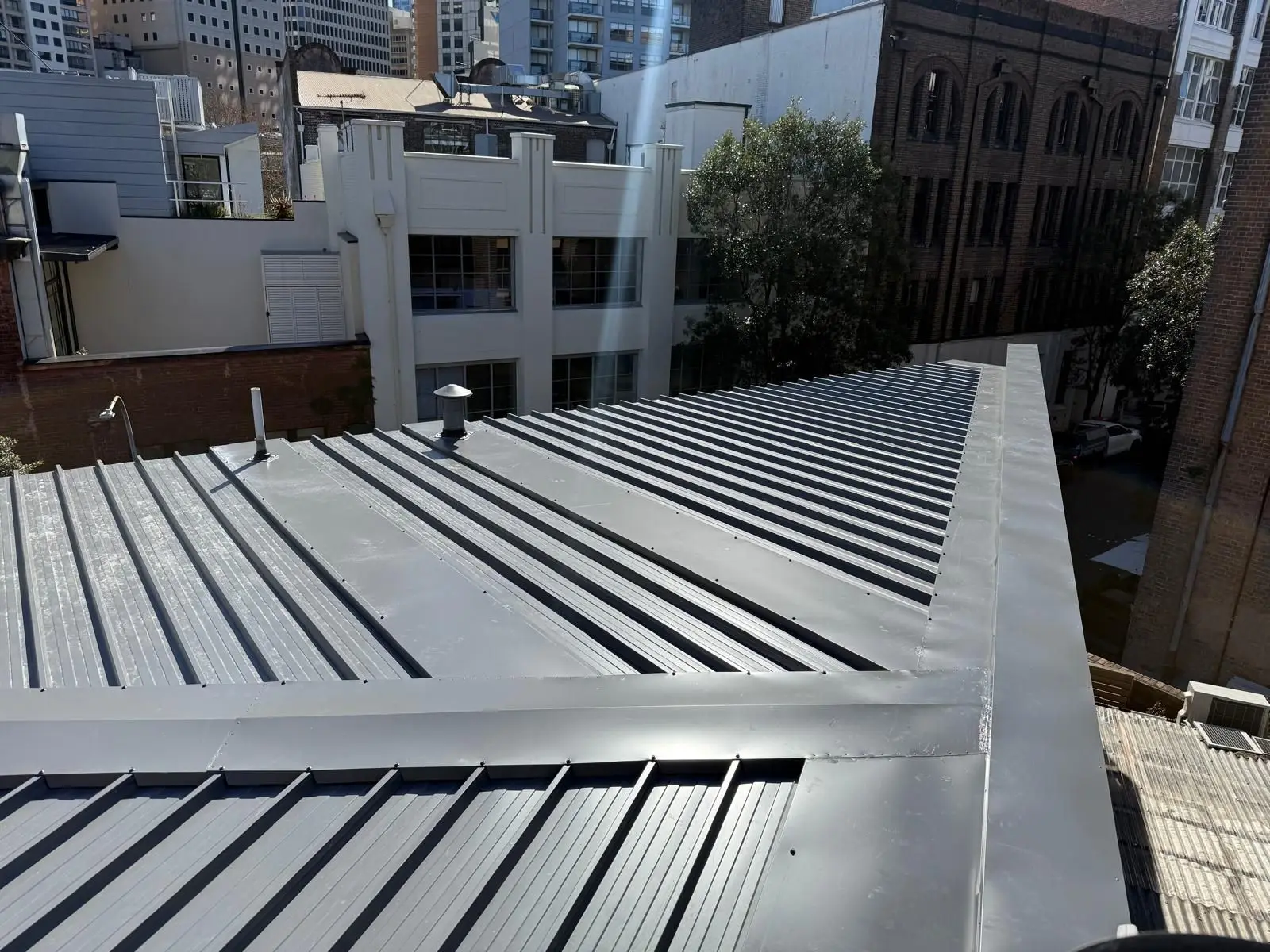 New standing-seam metal roof with its capping and flashings, surrounded by city buildings