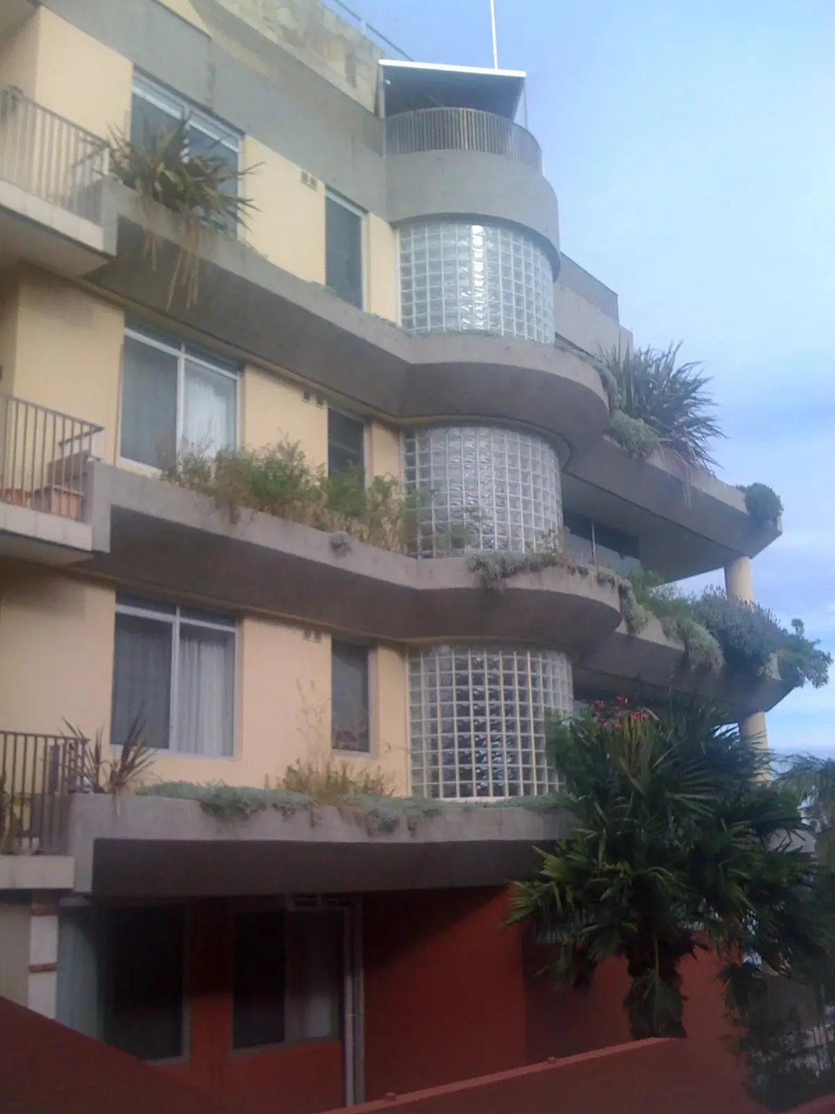 Planters on a curved facade, Planter boxes along the curved balconies of an apartment building with glass-block corners.