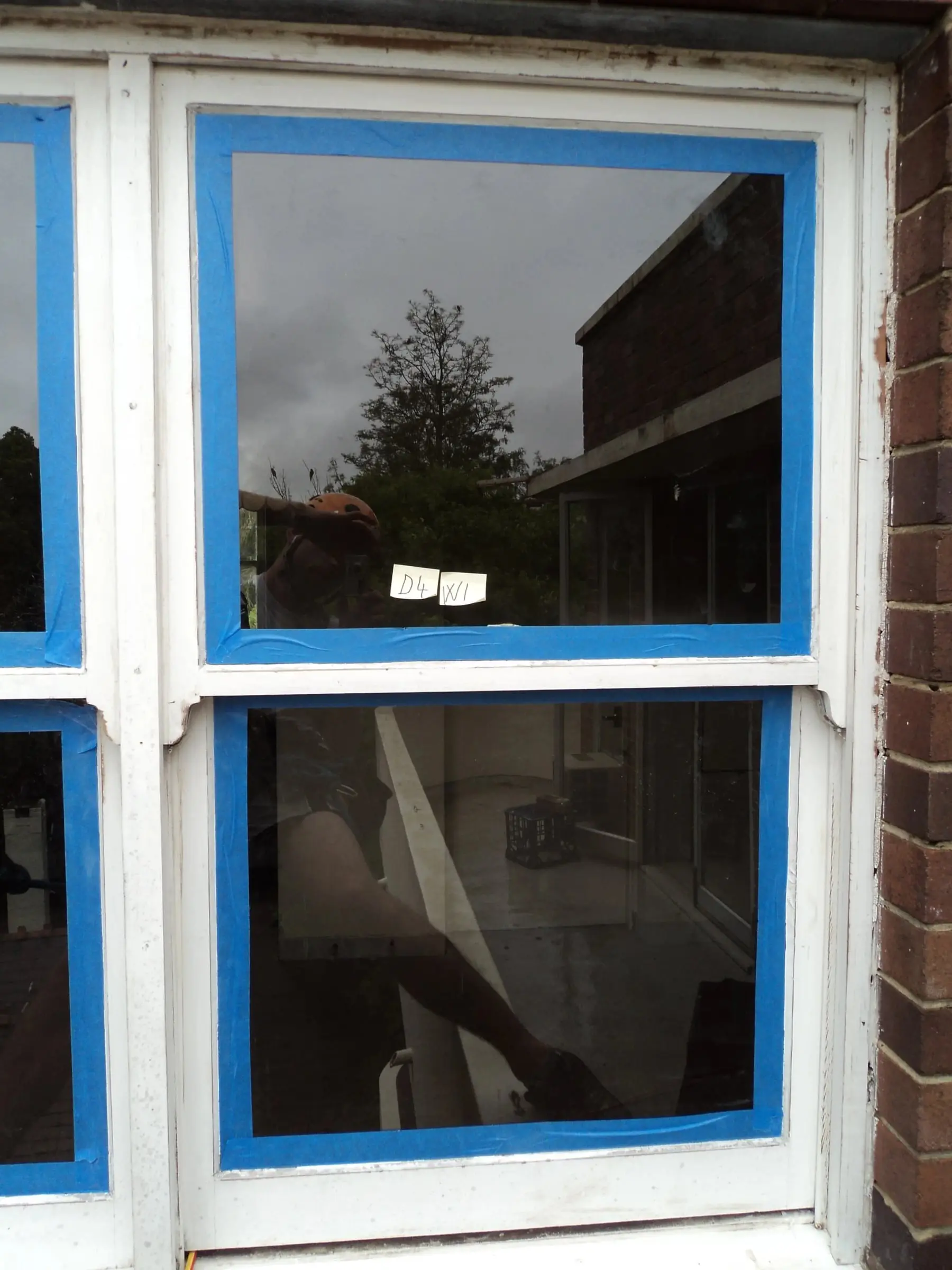 Frame prepared, A double-hung window in a brick wall with the glass masked off around the timber frame.