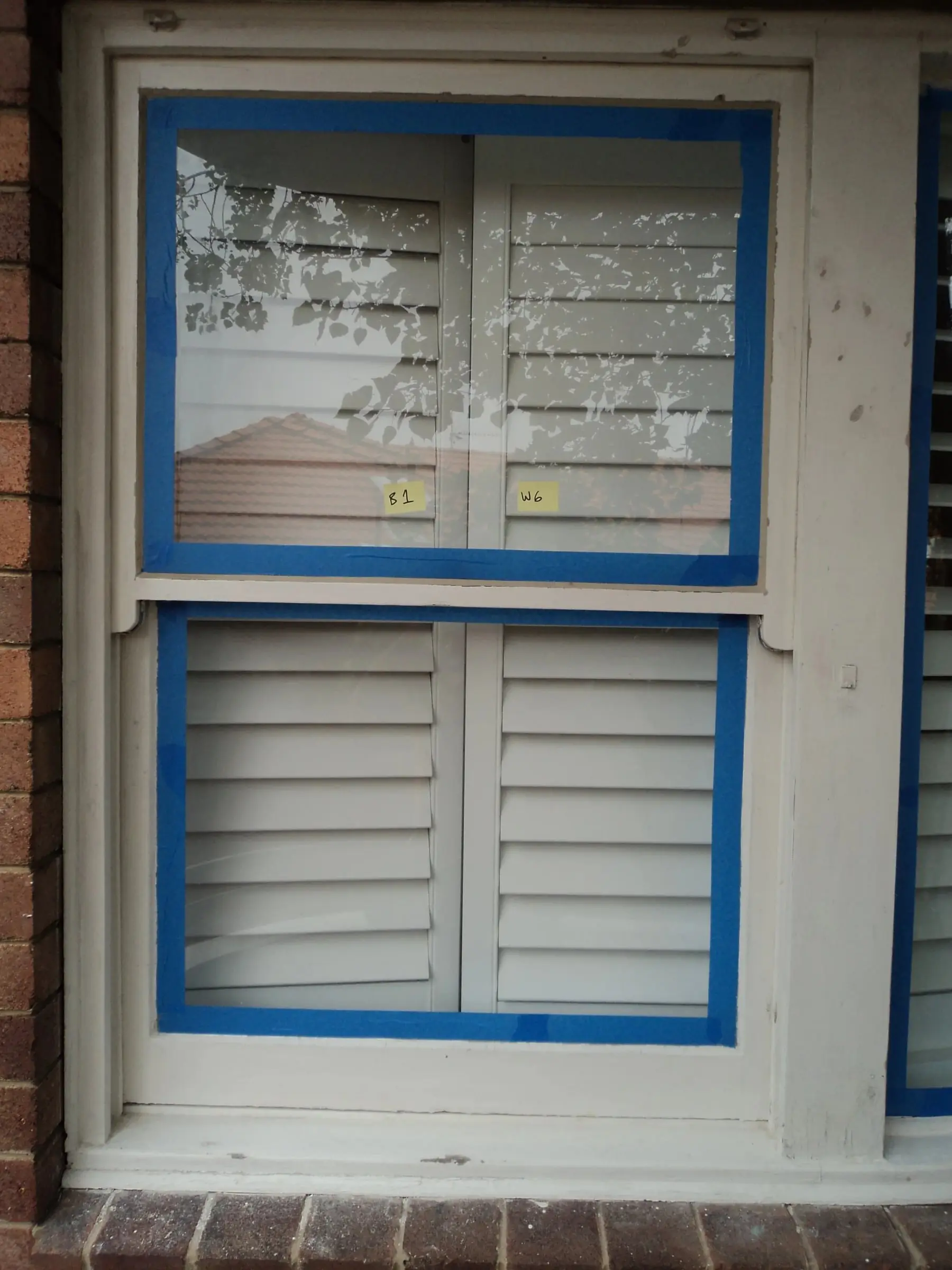 Sashes taped up, Upper and lower sashes masked in blue tape, with shutters visible inside.
