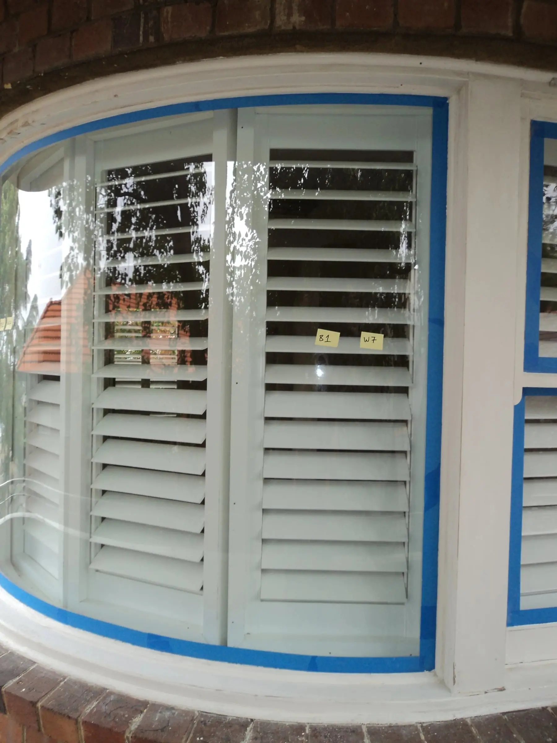 Curved bay window, A curved bay window with each pane masked in blue tape before refinishing.