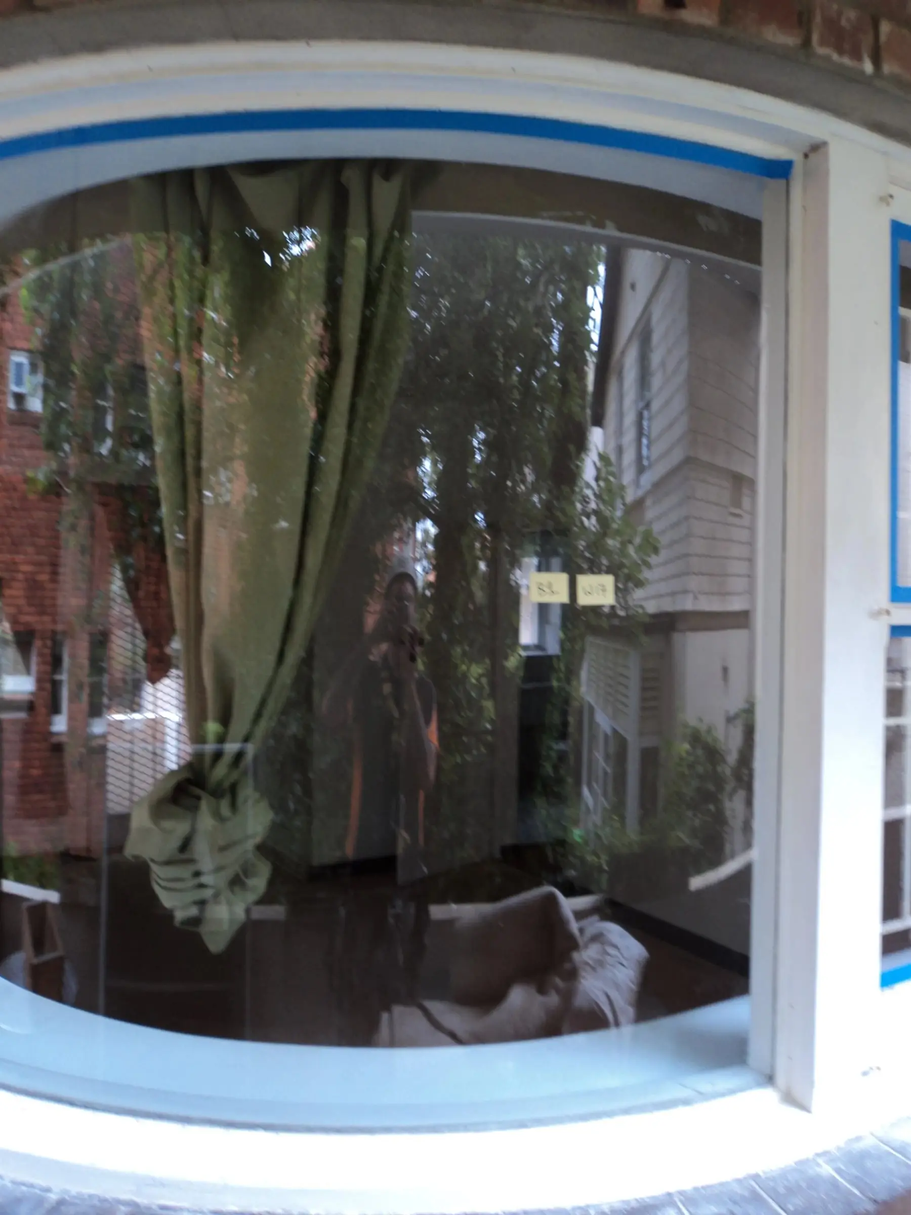 Bay window ready for paint, The curved timber frame of a bay window masked off from the glass.