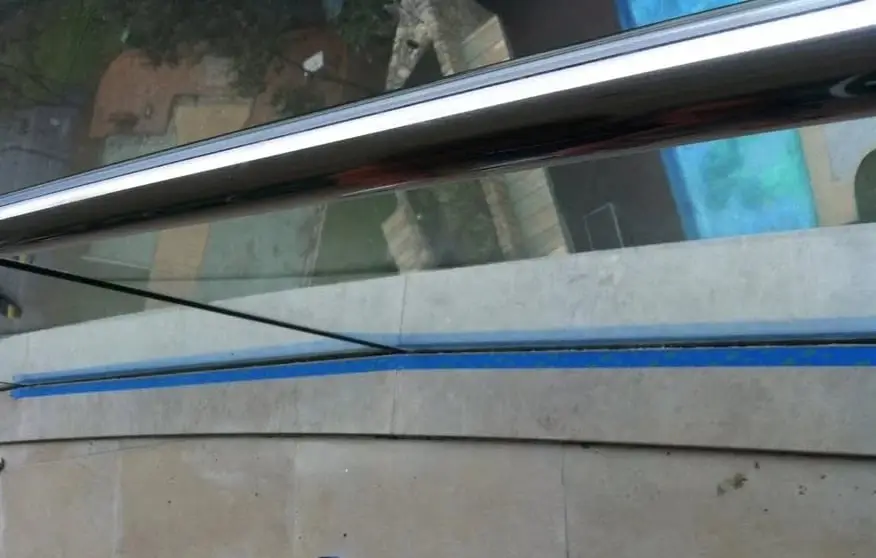 Masked for sealing, The stone base of a glass balustrade masked in blue tape along the joint to be sealed.